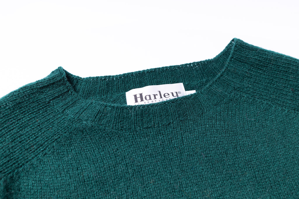 Green sweater with a visible brand label on a white background
