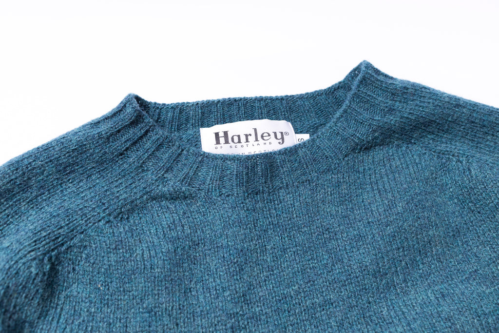 Blue sweater with a Harley of Scotland label on a white background
