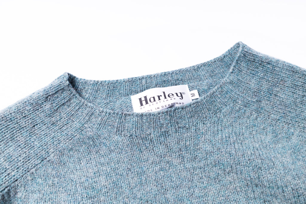 Close-up of a blue sweater with a Harley label on a white background