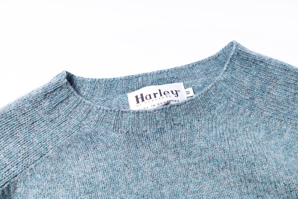 Close-up of a blue sweater with a Harley label on a white background