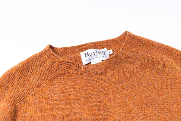 Close-up of an orange sweater with a Harley label on a white background