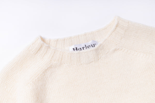 Close-up of a beige sweater with a 'Harley' label on a white background
