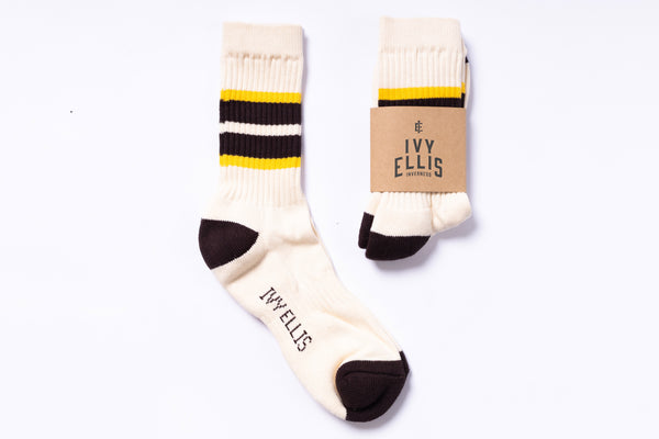 Pair of white socks with black and yellow accents and 'Ivy Ellis' branding on a white background.
