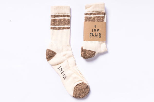 Pair of cream socks with brown accents and a matching cardboard packaging on a white background