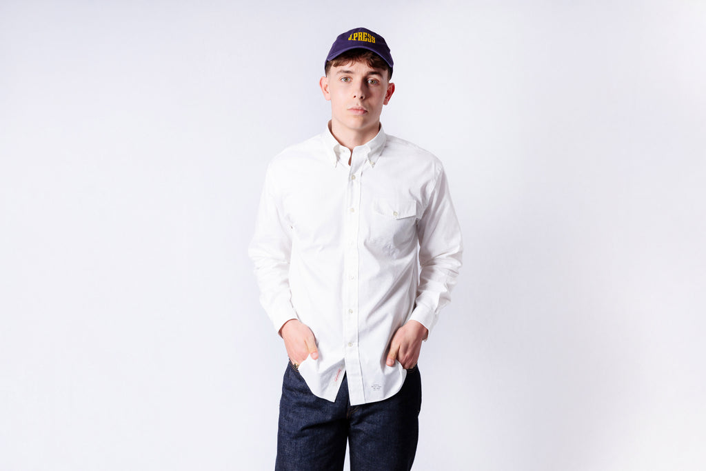 Person wearing a white shirt and dark pants with a cap on a white background