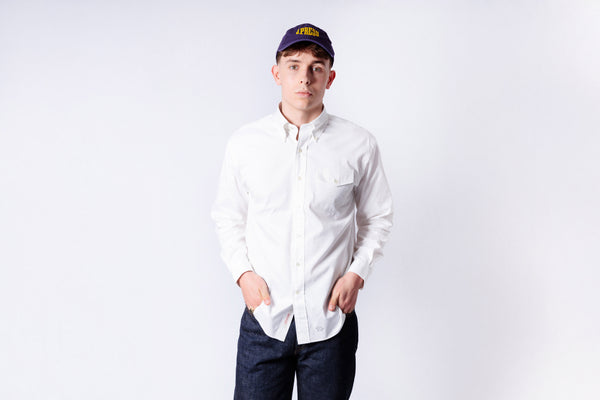 Person wearing a white shirt and dark pants with a cap on a white background