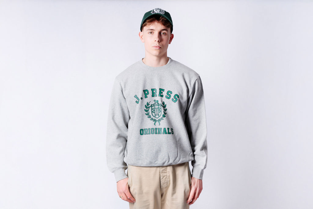 Person wearing a gray sweatshirt with branding on a white background