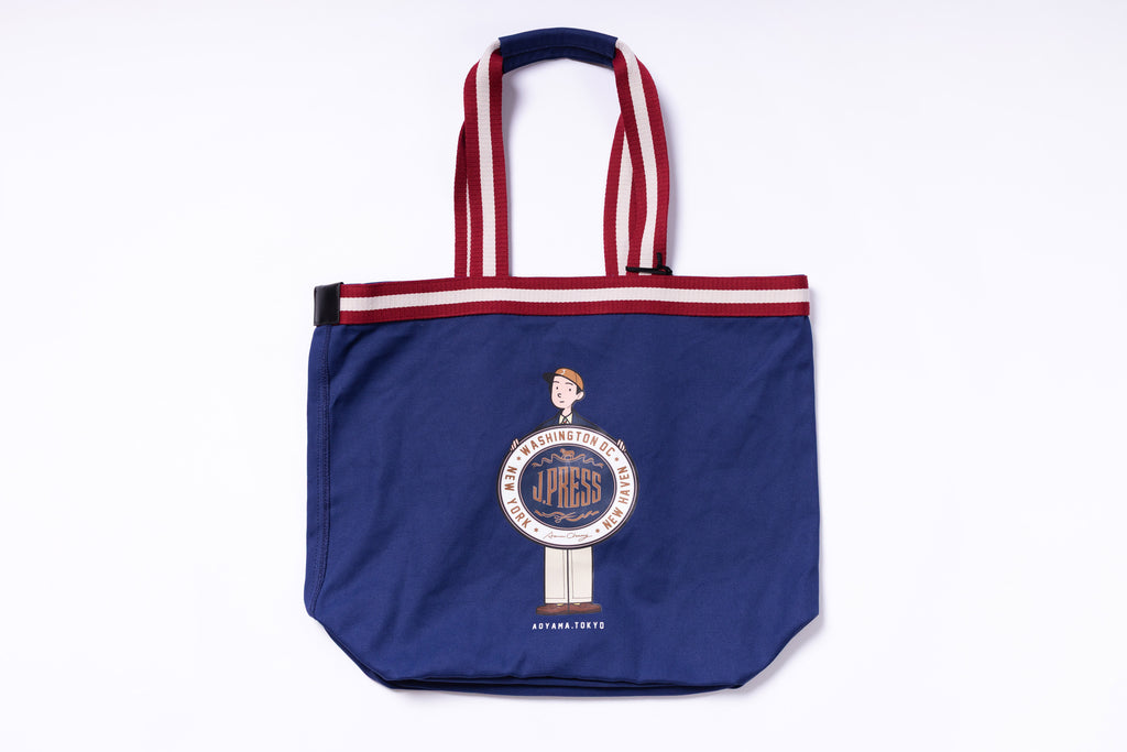 Blue tote bag with red and white striped handles on a white background