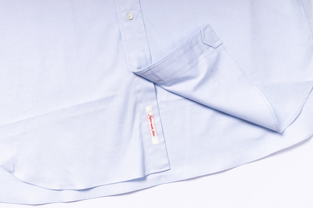 Light blue dress shirt with a collar and label on a white background