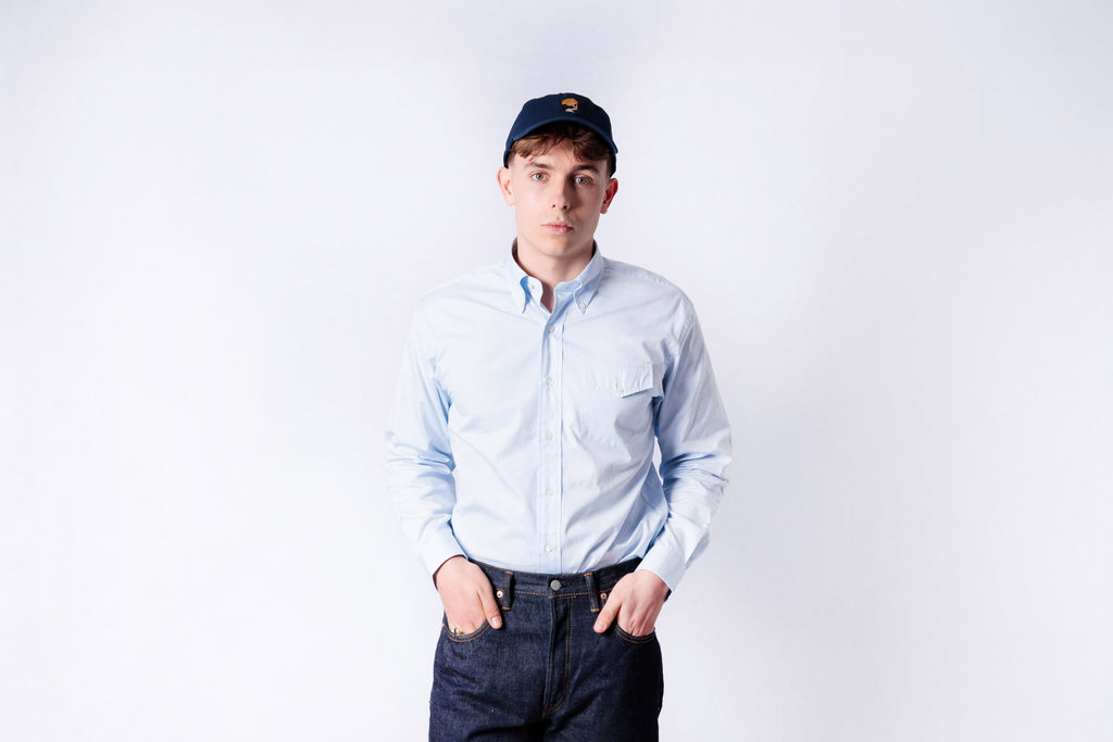 Person wearing a light blue shirt and dark pants on a white background
