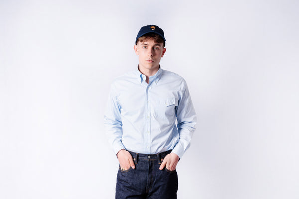Person wearing a light blue shirt and dark pants on a white background