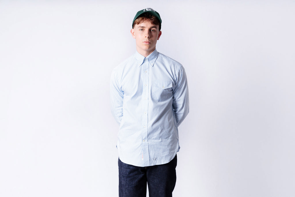 Person wearing a light blue shirt and dark pants on a white background
