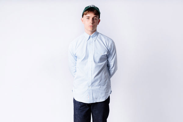 Person wearing a light blue shirt and dark pants on a white background