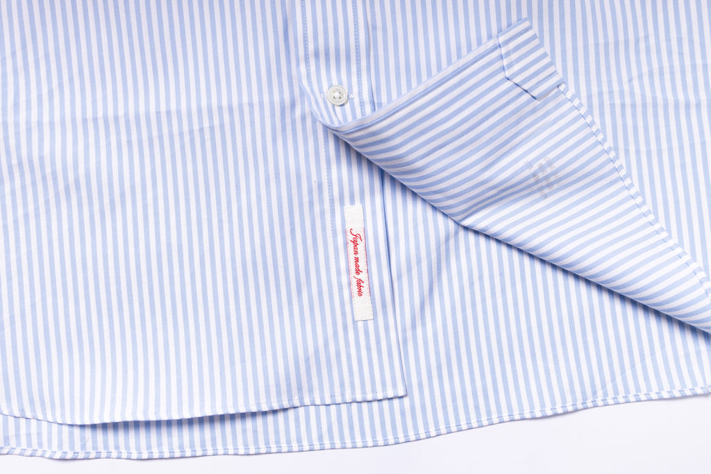 Close-up of a blue and white striped shirt with a brand label on a white background