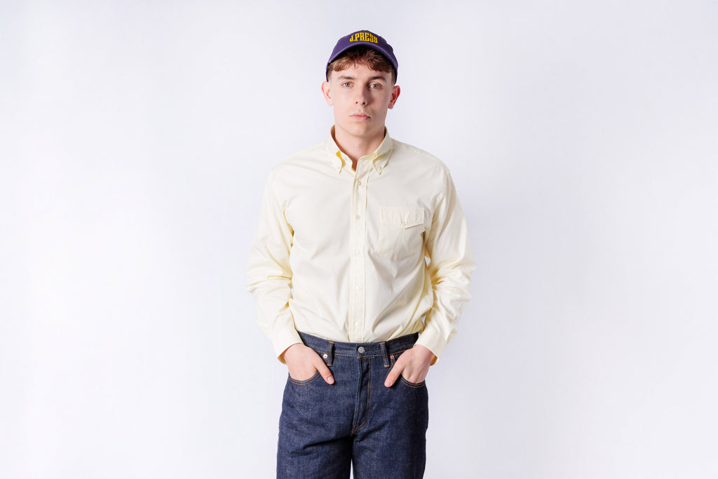 Person wearing a light-colored shirt and dark jeans on a white background