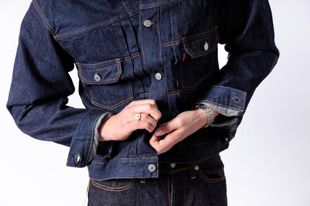 Person wearing a dark blue denim jacket on a white background