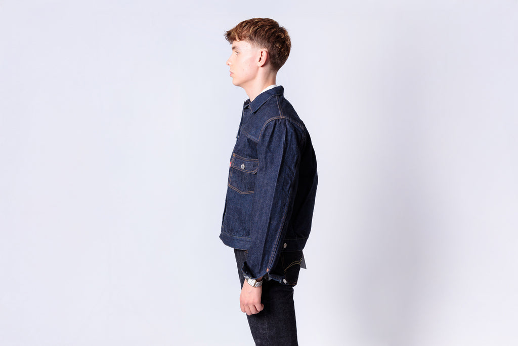 Person wearing a dark denim jacket on a light gray background