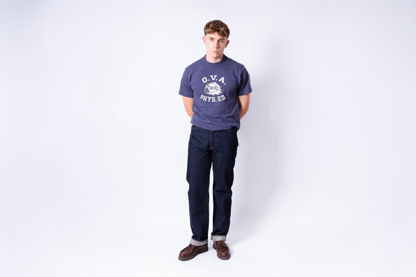 Person wearing a navy blue 'O.V.A' t-shirt and dark pants on a white background