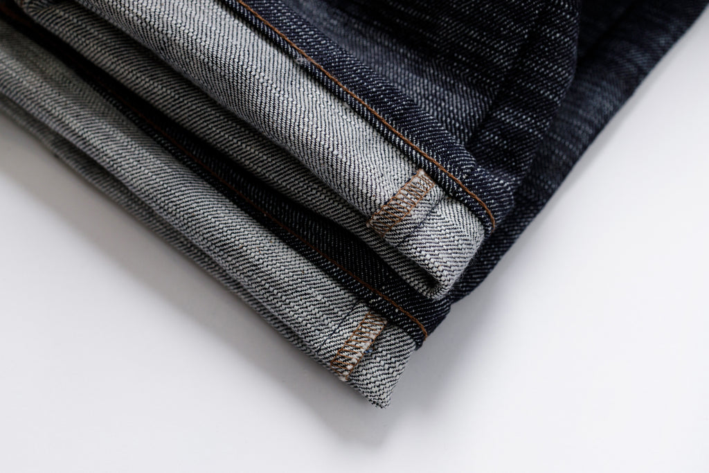 Stack of folded denim jeans on a white background