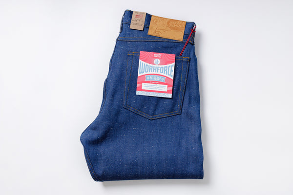 Folded blue denim jeans with a brand label on a white background