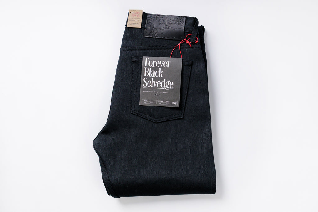 Folded black selvedge jeans with a label on a white background