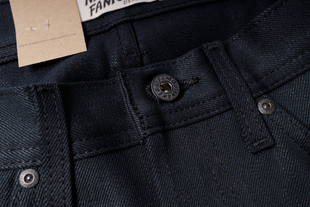 Close-up of dark denim fabric with buttons and a tag.