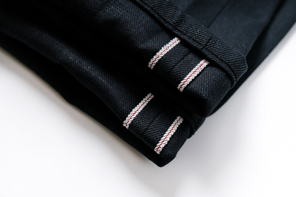 Close-up of black fabric with red and white stitching on a white background