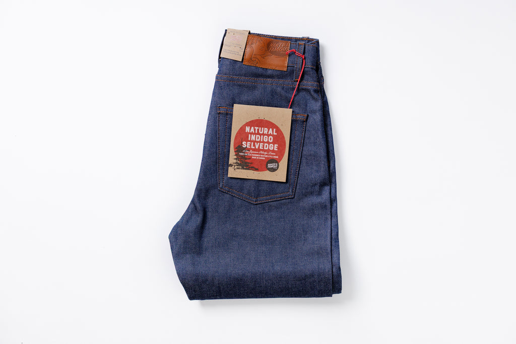 Folded pair of blue jeans with a label on a white background