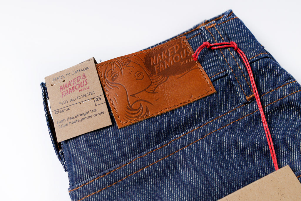 Close-up of blue jeans with a brand label on a white background