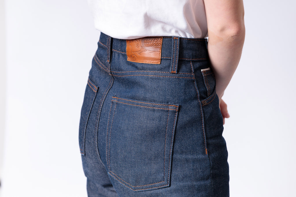 Blue jeans with a brown leather patch on a white background