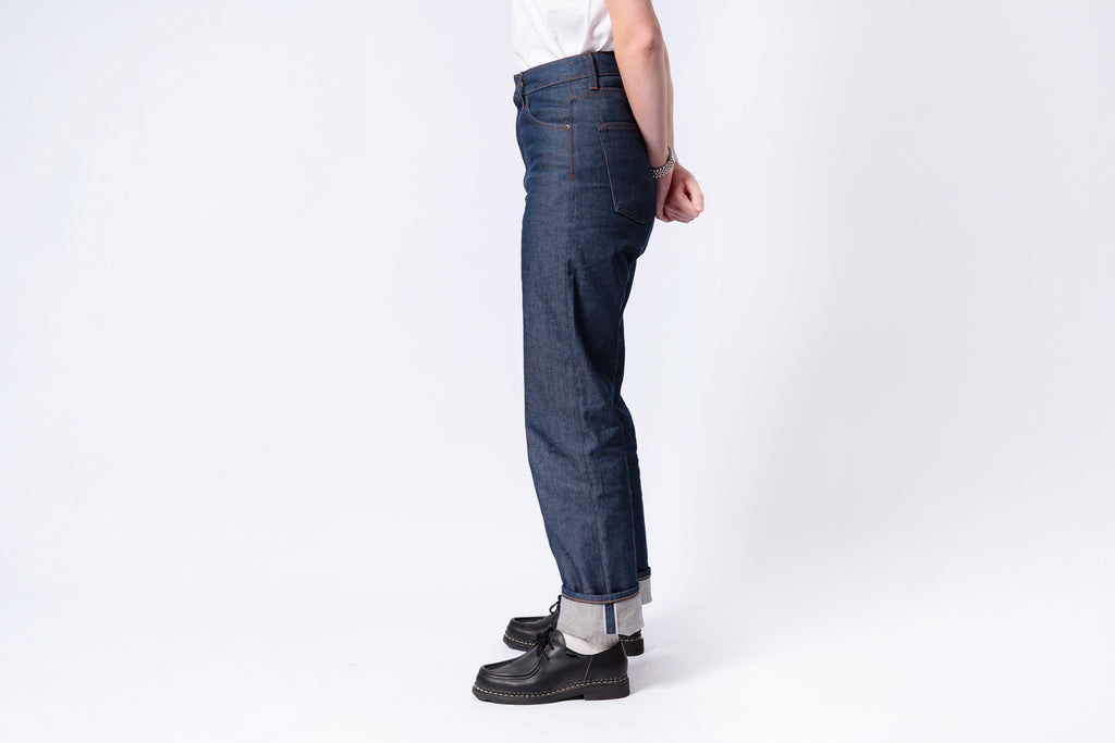 Person wearing dark blue jeans and black shoes on a white background