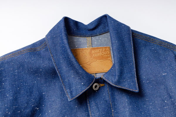 Close-up of a blue denim shirt with a brand label on a white background