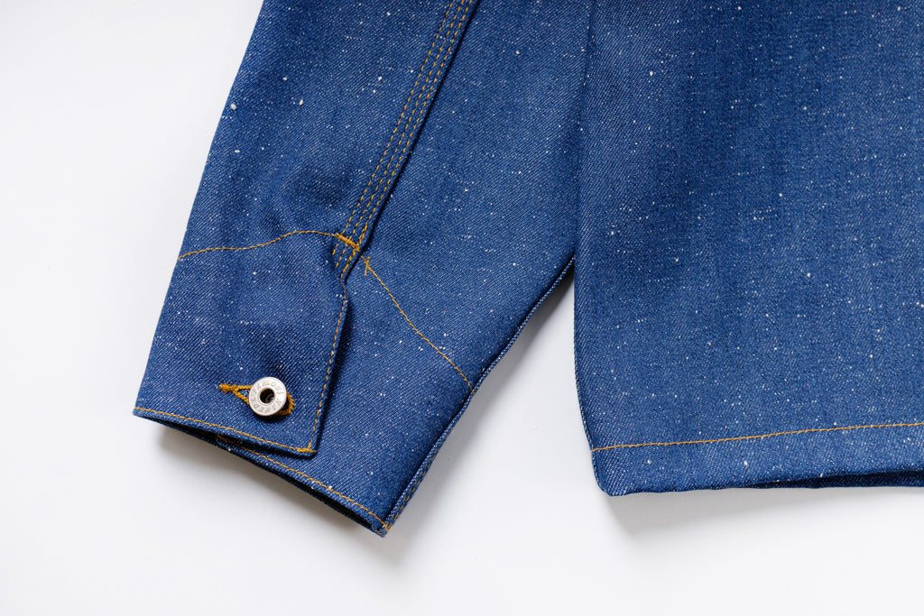 Close-up of blue denim fabric with a button on a white background