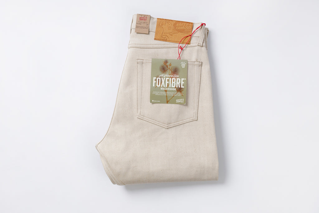 Folded beige jeans with a visible brand label on a white background