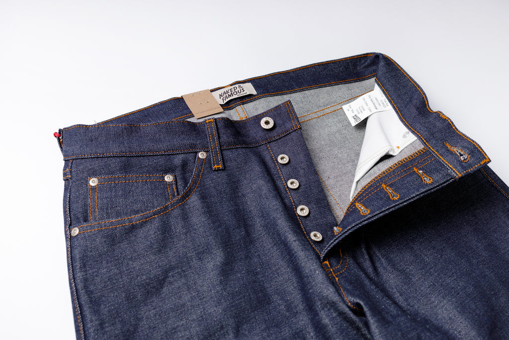 Blue denim jeans with button details on a white background