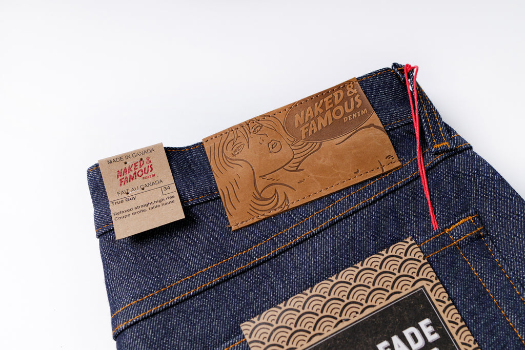 Close-up of blue jeans with brand labels on a white background