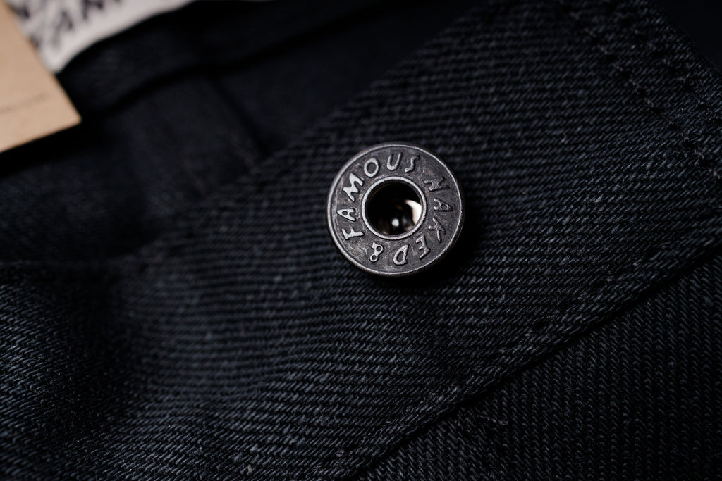 Close-up of a button on black fabric with 'Famous' branding.