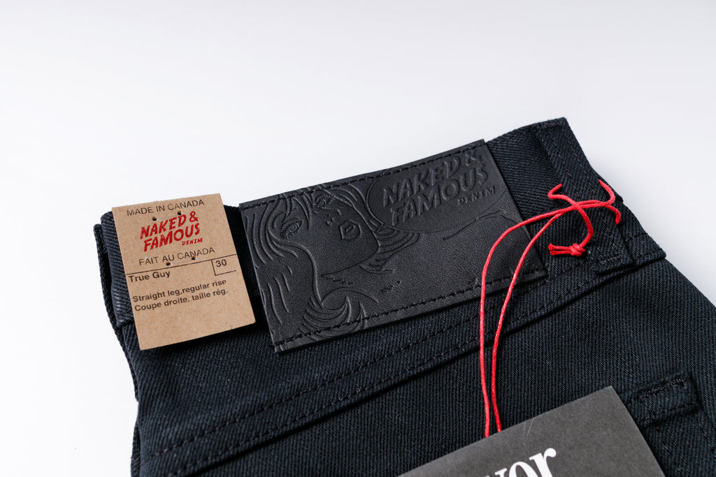 Black denim jeans with a brand label and tag on a white background