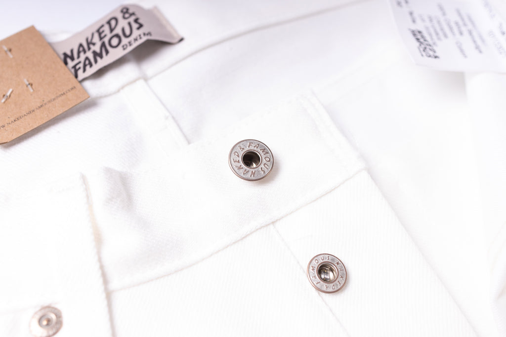 Close-up of a white shirt with buttons and a 'Naked & Famous' label.