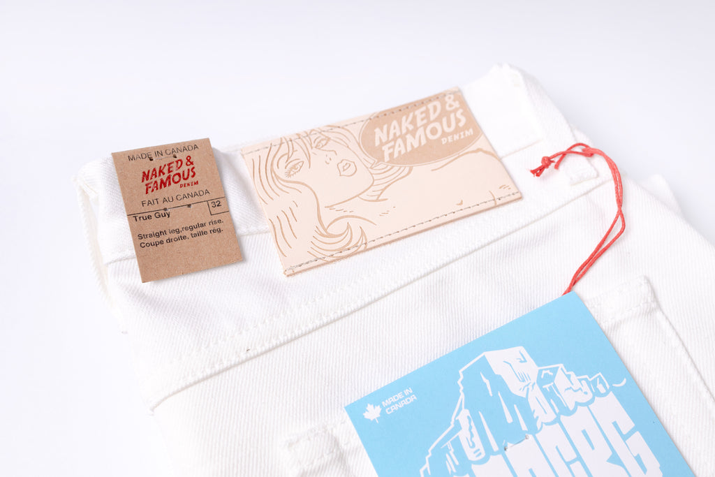 Naked & Famous bath salt packaging with a white drawstring bag on a light background