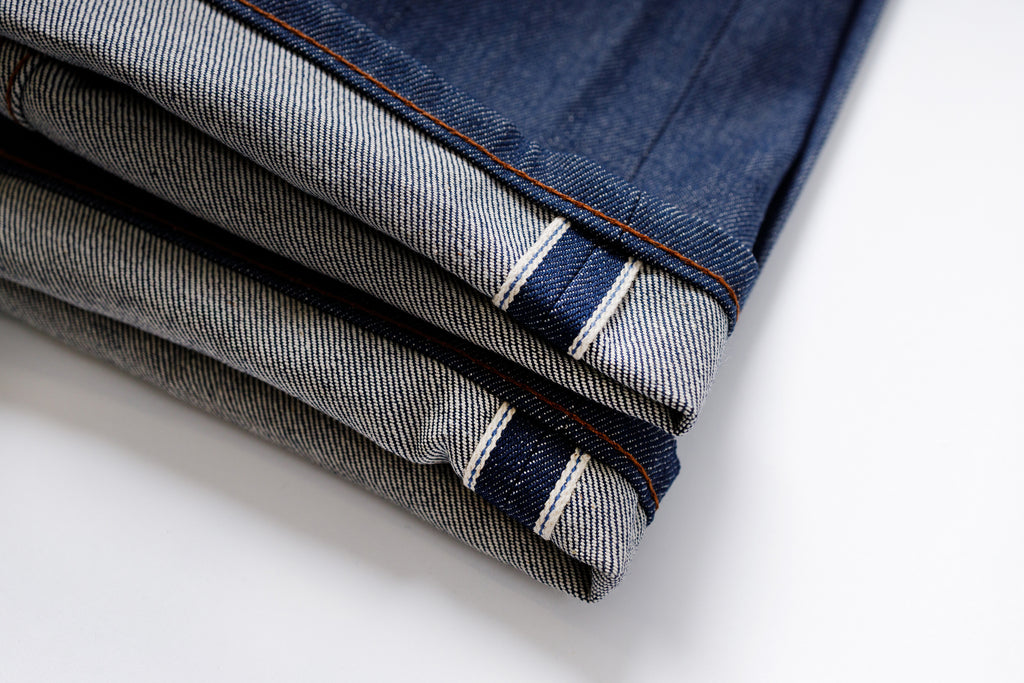 Stack of folded denim jeans on a white background