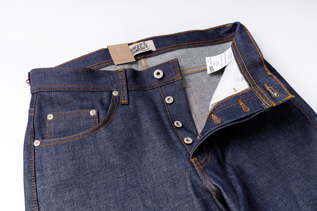Close-up of a pair of blue jeans with visible stitching and buttons on a white background