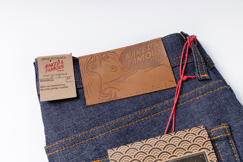 Close-up of a denim product with 'Naked & Famous' label on a white background