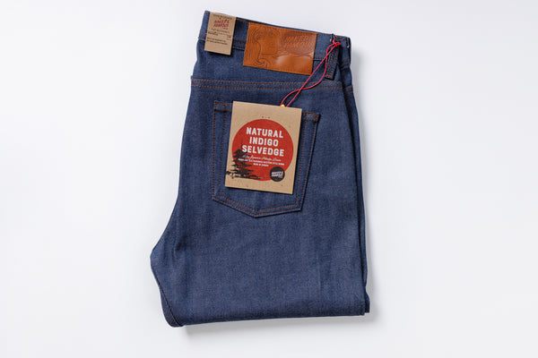 Folded pair of blue jeans with a brand label on a white background