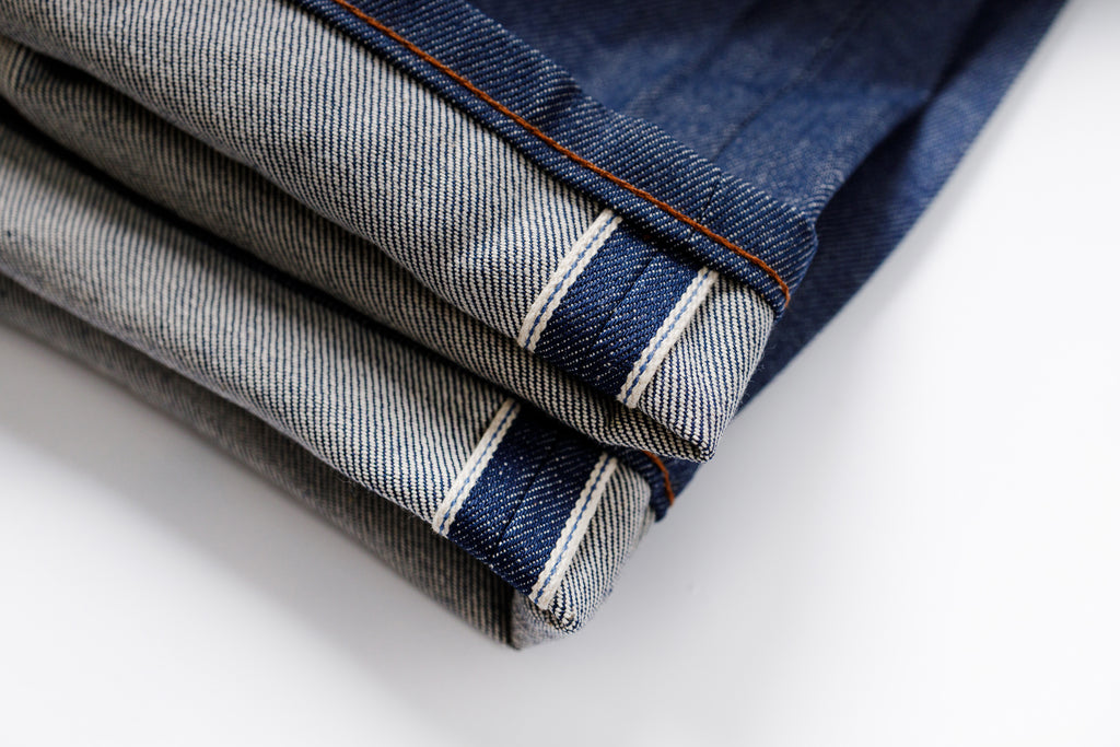 Stack of folded denim jeans on a white background