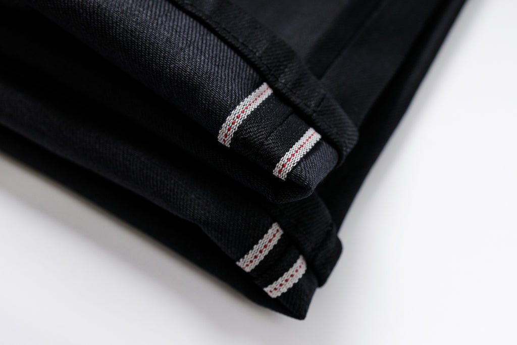 Folded black fabric with white stitching on a light background