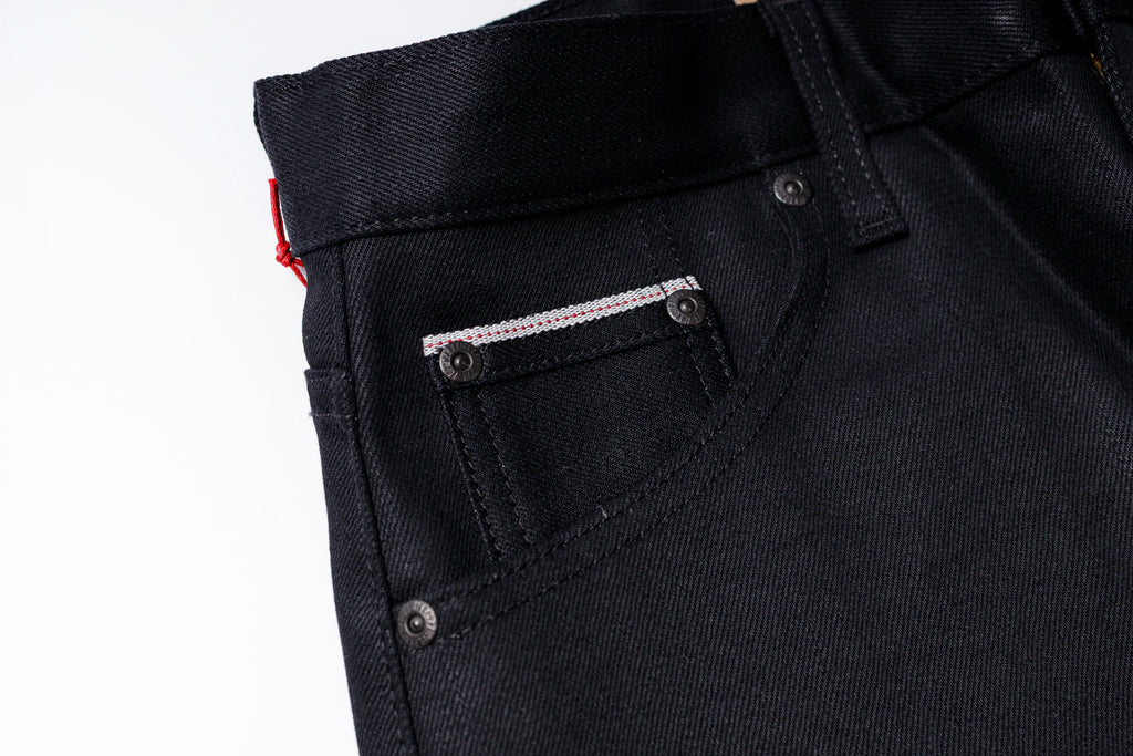 Close-up of black jeans with a pocket detail on a white background