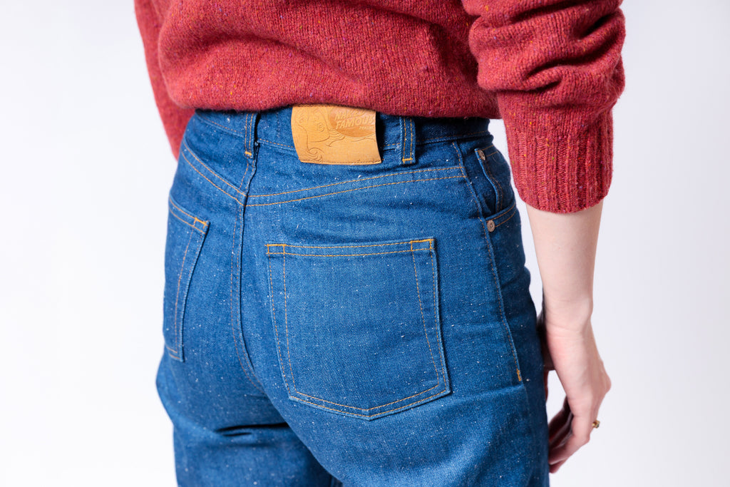 Person wearing blue jeans and a red sweater with a white background