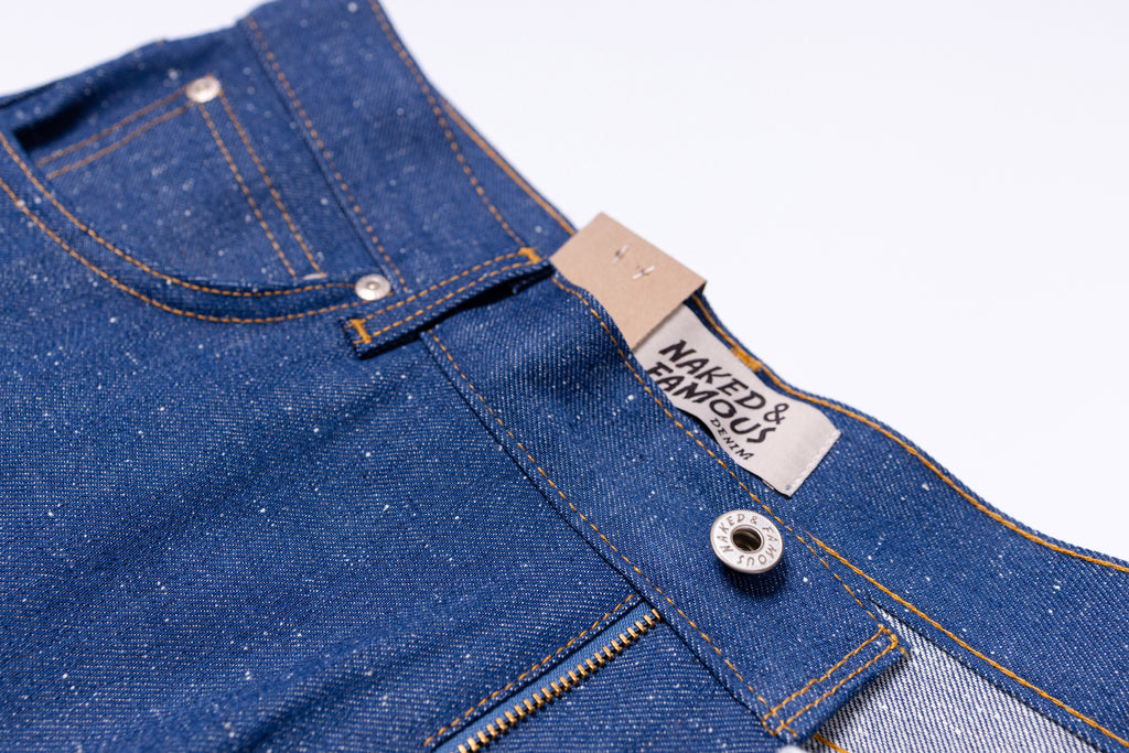 Close-up of blue denim jeans with a brand label on a white background