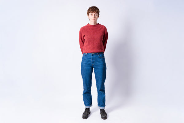 Person wearing a red sweater and blue jeans on a white background